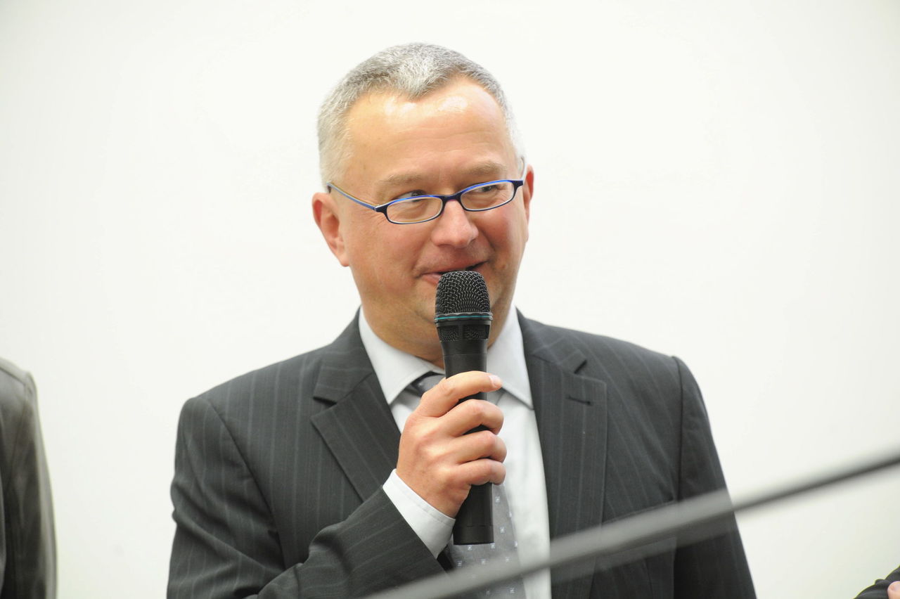 Foto: Mann im grauen Anzug am Mikrofon