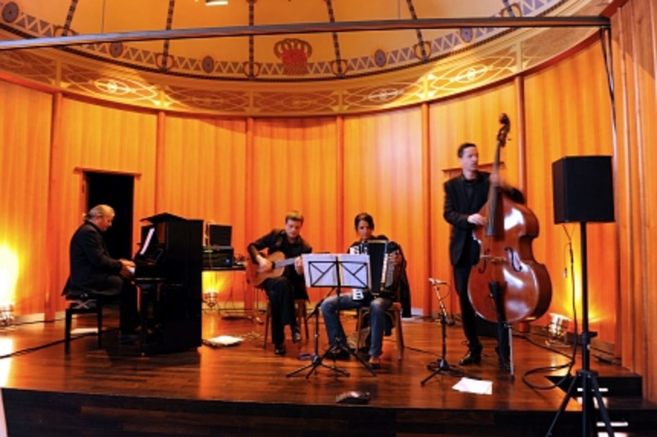 Foto: Ein Quartett aus Piano, Gitarre, Akkordeon und Bass beim abendlichen Empfang