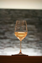 Foto: Nahaufnahme eines mit Burgunder gefüllten Weinglases vor einer grauen Steinwand.