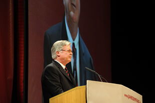 Foto: Dr. Augter am Rednerpult, im Hintergrund sein Bild auch auf der Großleinwand