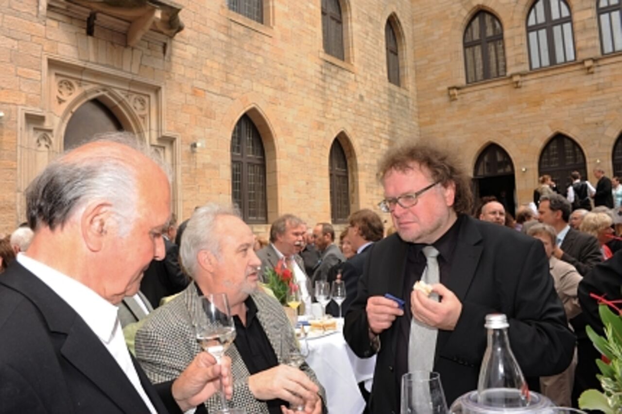 Foto: Drei Herren beim Imbiss und im Gespräch.