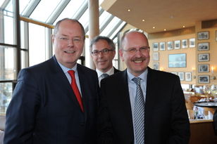 Foto: Drei Herren lächeln in die Kamera, links Peer Steinbrück