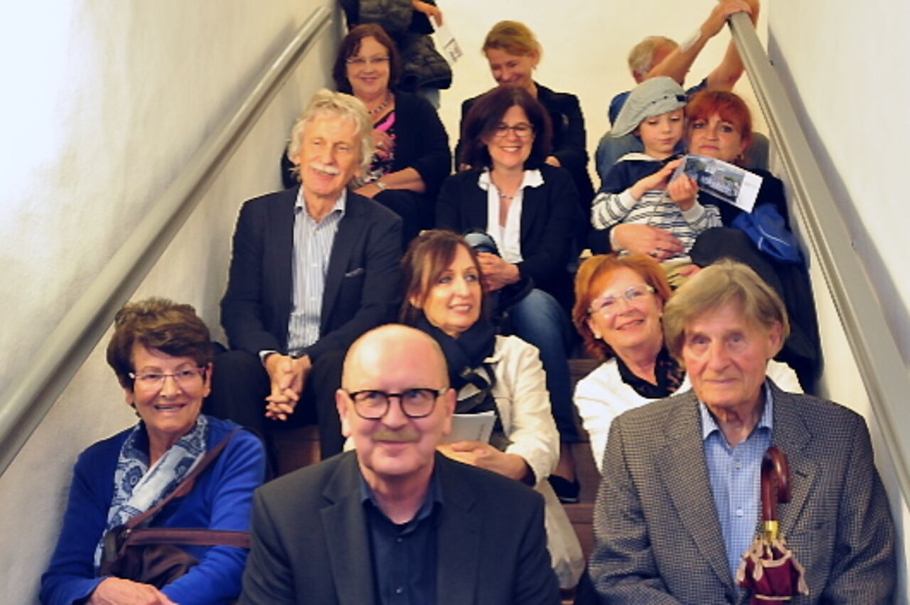 Fröhliche Gesichter beim Gruppenbild einiger Teilnehmer, die auf einer Treppe sitzen.