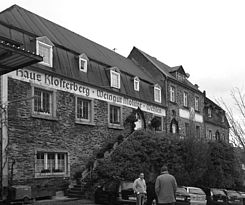 Foto: Die Fassade des Haus Klosterberg vor der Sanierung mit Büschen bewachsenem Treppenaufgang.