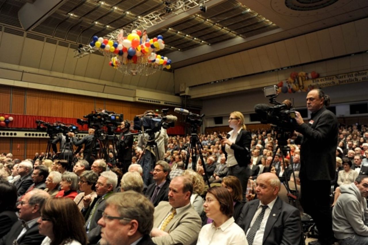 Foto: Blick in den vollbesetzten großen Saal der Rheingoldhalle und auf zahlreiche Kameras