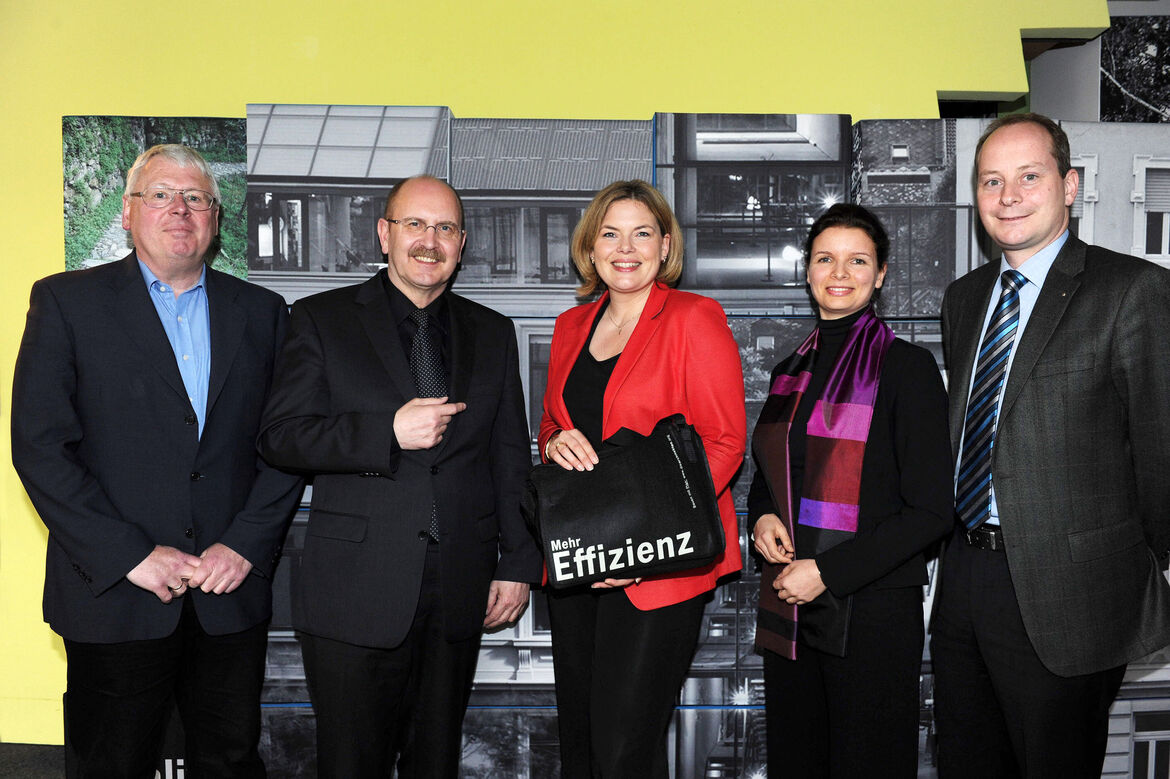 Foto: Fünf lächelnde Menschen im Bild. Eine Dame in der Mitte präsentiert die Tasche mit dem Kammerslogan "Mehr Effizienz"