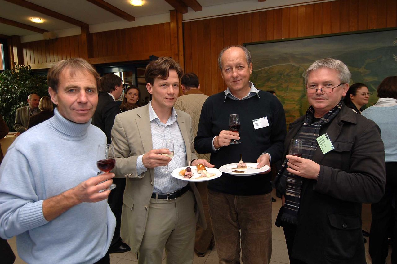 Vier Männer mit Weingläsern und Tellern