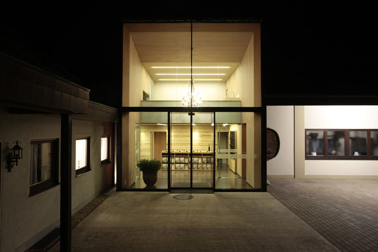 Foto: Nachtaufnahme, hell erleuchteter, verglaster Eingang
