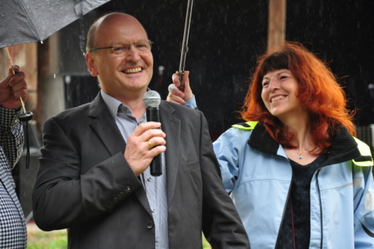 Ein Mann mit Mikrophon und eine Frau mit Regenschirm