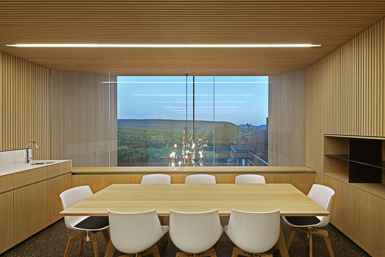 Foto: Blick aus einem mit hellem Holz vertäfelten Raum durch ein großes Fenster in die Landschaft