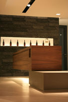 Foto: Blick auf den schwebenden Verkostungstresen aus hellem, heimischen Holz. Im Hintergrund sieht man ein in die Wand eingelassenes Präsentationsregal für die Weine.