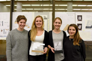 Vier junge Frauen, davon zwei mit einem kleinen Modell ihres Pokalentwurfs in der Hand, lächeln in die Kamera.