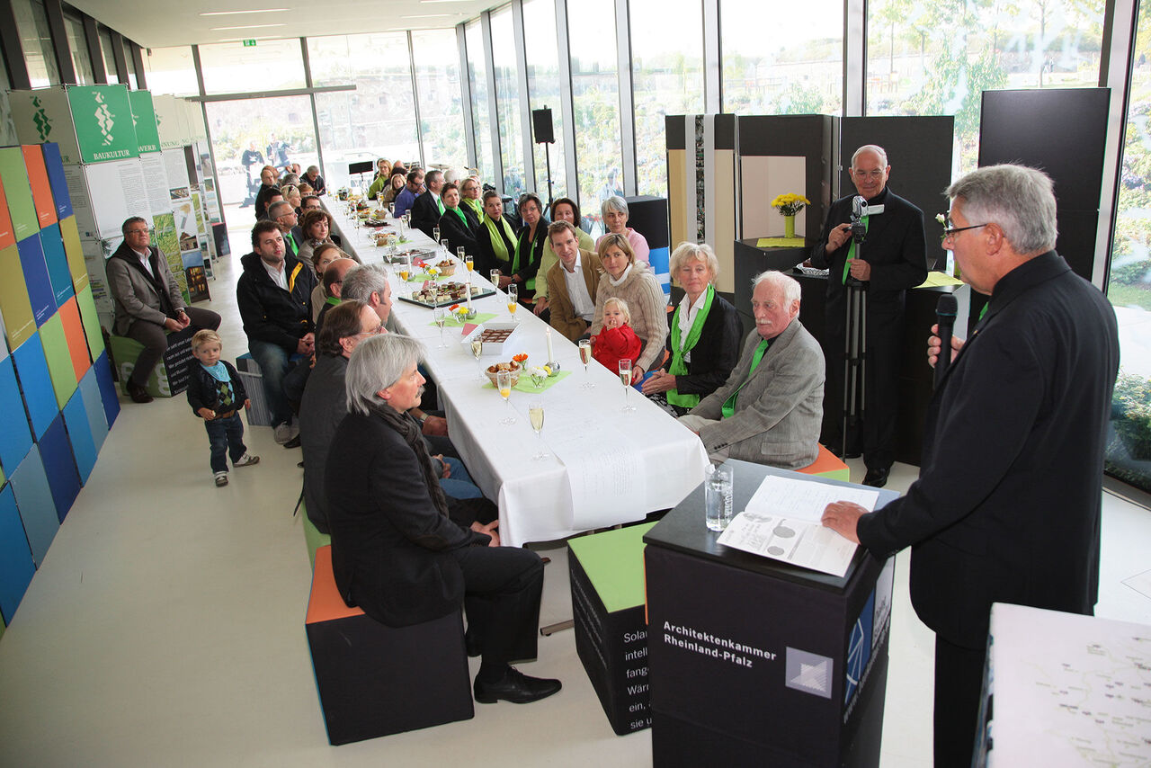 Lange Tafel, Redner an Pult im Vordergrund