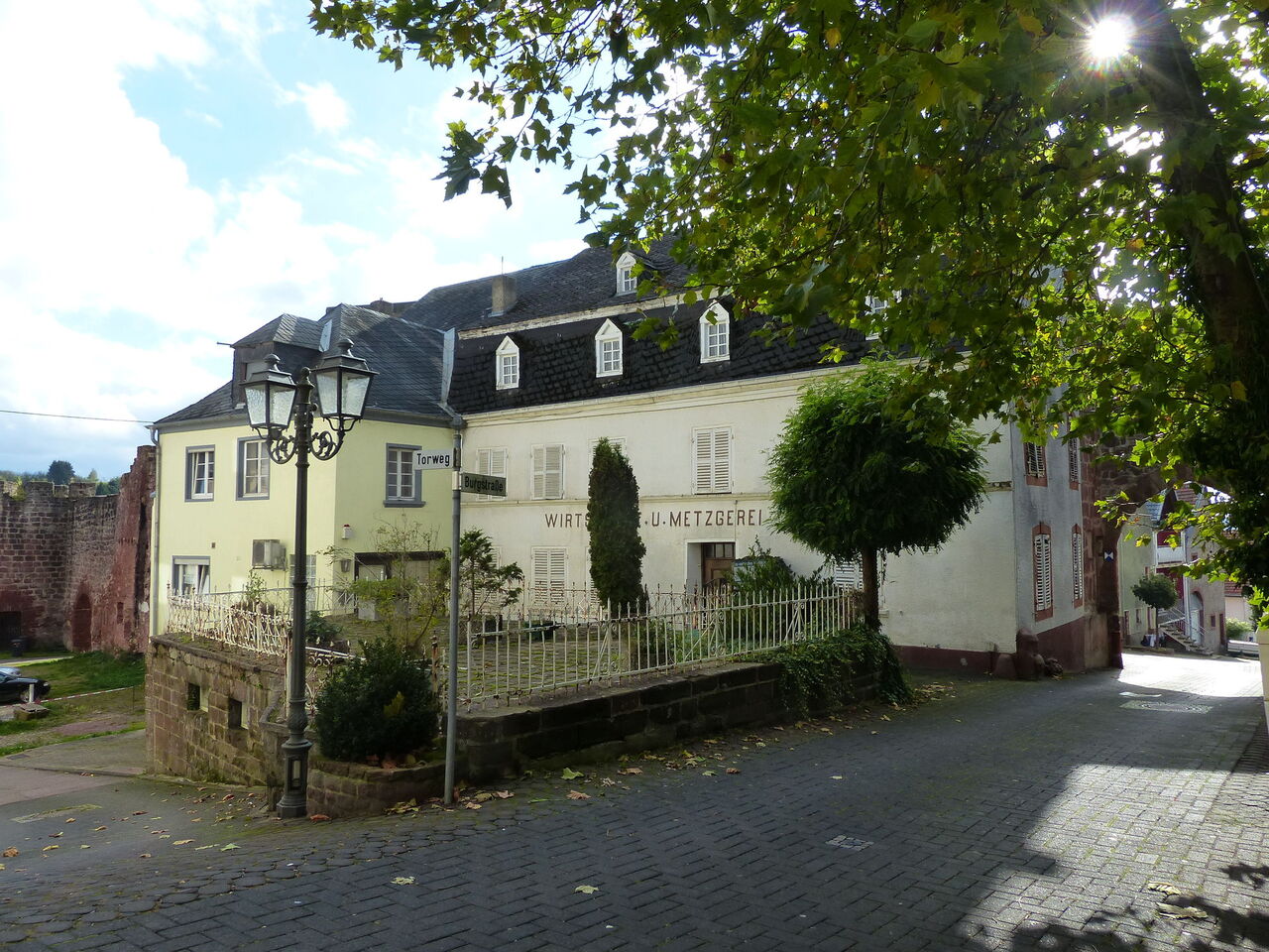 Ein dekorativer altweißer Altbau mit eingemauertem Vorgarten im Stil eines Gasthauses.