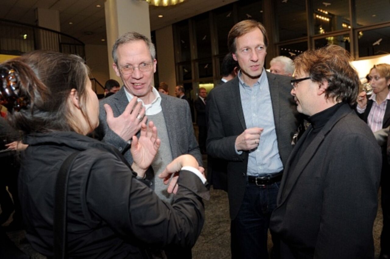 Foto: Drei Männer und eine Frau sind gestikulierend ins Gespräch verwickelt.