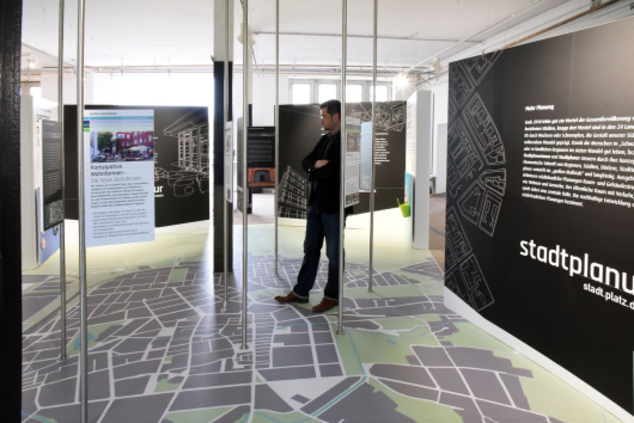 Ein Blick in die Dauerausstellung zeigt die Wandelemente mit Informationen, auf den Boden aufgebracht ein großflächiger Stadtgrundriss von Landau.