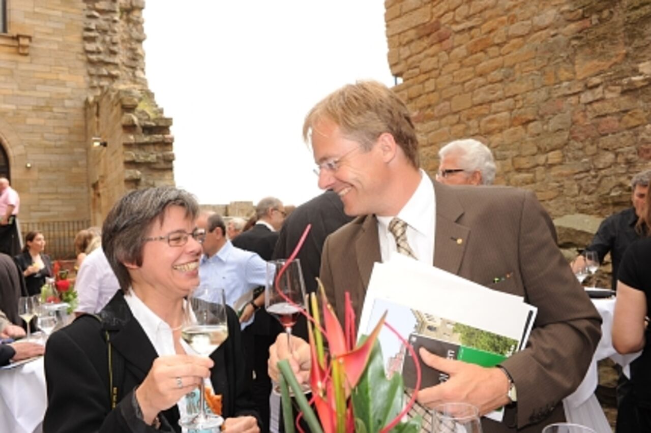 Foto: Eine Frau und ein Mann lächeln sich an und prosten sich zu.