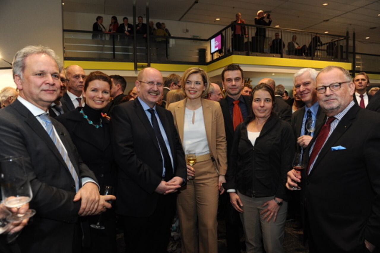 Foto: Gruppenbild im vollen Saal mit fünf Männern und zwei Frauen. 