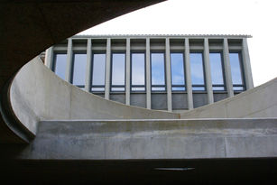 Blick aus einer der großen Licht- und Luftöffnungen der Tiefgarage auf die klare Struktur des denkmalgeschützten Gebäudes