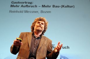 Foto: Reinhold Messner im Vordergrund, der Titel seines Vortrages im Hintergrund