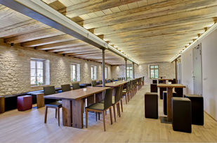 Foto: Im Seminarraum der sich im Dachgeschoss befindet wurde die Holzbalkendecke freigelegt. Dadurch wirkt der Raum offen und großzügig.