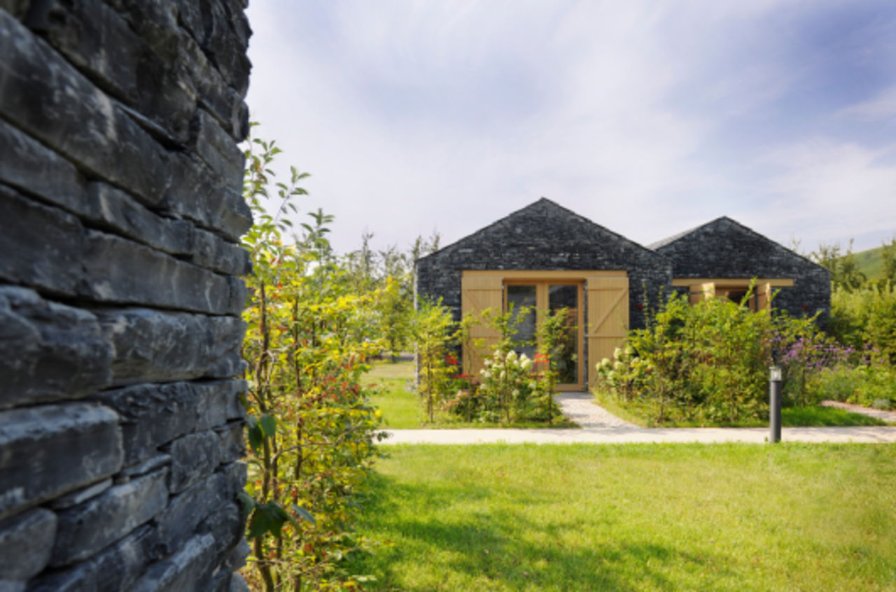 Foto: Blick in den Garten auf zwei Winzerhäuser aus dunklem Stein vor denen sich jeweils ein kleiner Garten befindet