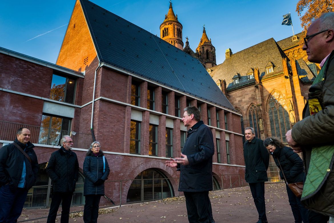 Cirka achte Personen vor dem Neubau, im Hintergund der Wormser Dom.