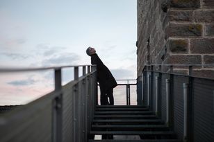 Blick über den Steg zu Tür zum Burgturm mit einem Herren davor, den Blick nach oben gerichtet.