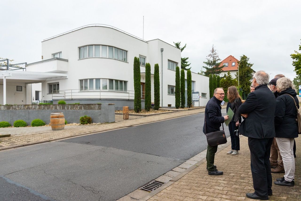 eine kleine Personengruppe vor der runden Ecke des Weinguts