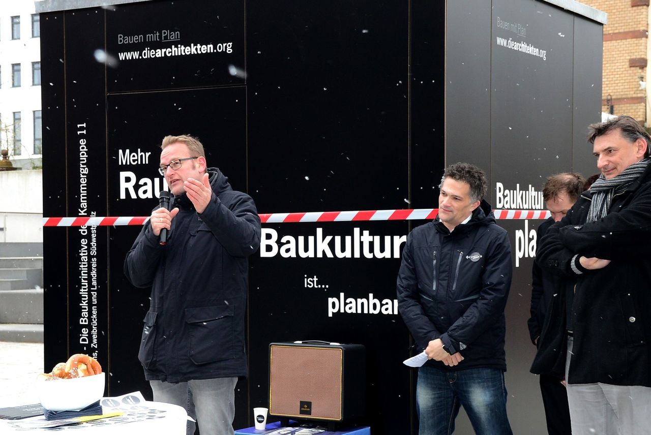 Herr Zwick spricht vor der Baukulturbox und man sieht leichten Schneefall.