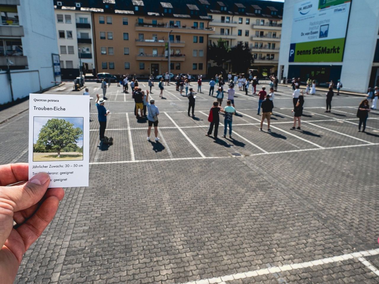 Besuchergruppe auf dem Parkplatz eines Supermarktes. "walk about... talk about... Koblenz" mit Bertram Weisshaar im Juni 2021.