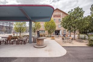 Ansicht der Markthalle, im Vordergrund eine ehemalige Tankstelle