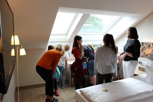 Schülergruppe im Hotelzimmer mit Dachschräge und Dachflächenfenster.