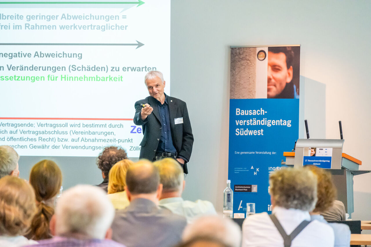 Prof. Zöller zeigt ins Publikum bei seinem Vortrag.