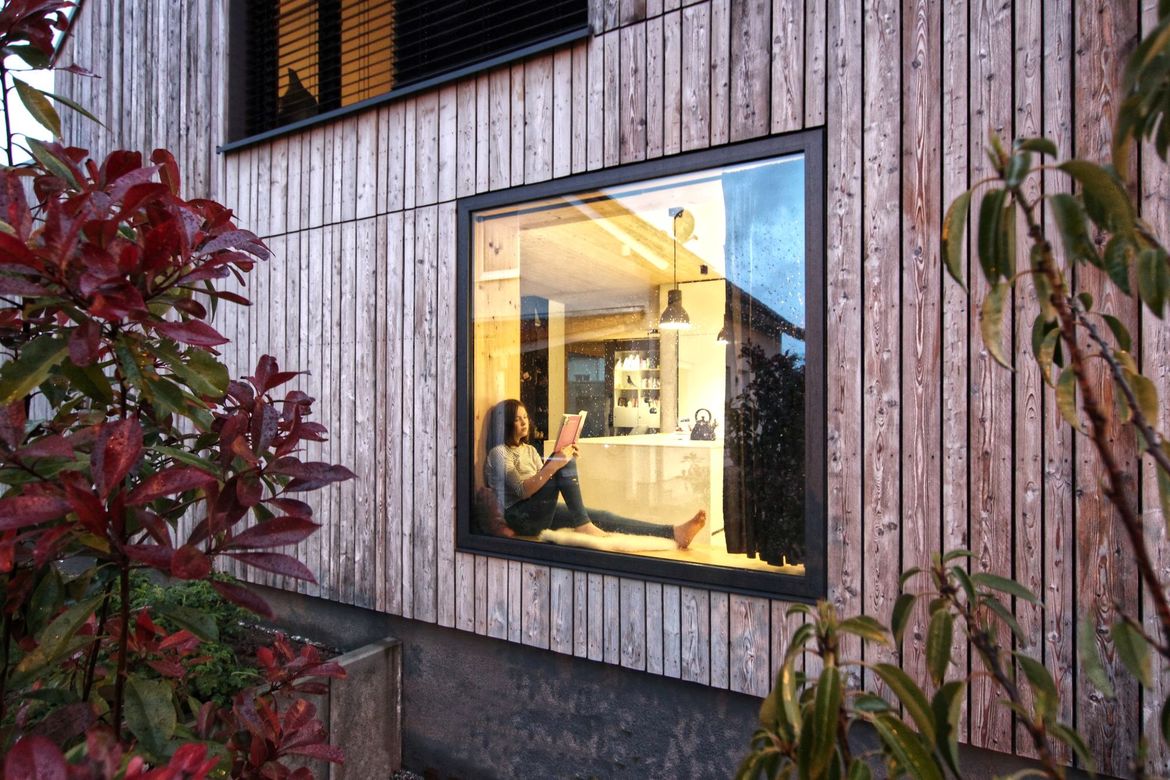 Holz-Fassade mit großem festverglasten Fenster.