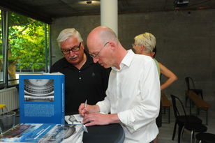 Foto: Kristina Schäfer, Mainz Sascha Salzig beim signieren seines Buches am Stehtisch, der gleichzeitig Büchertisch ist.
