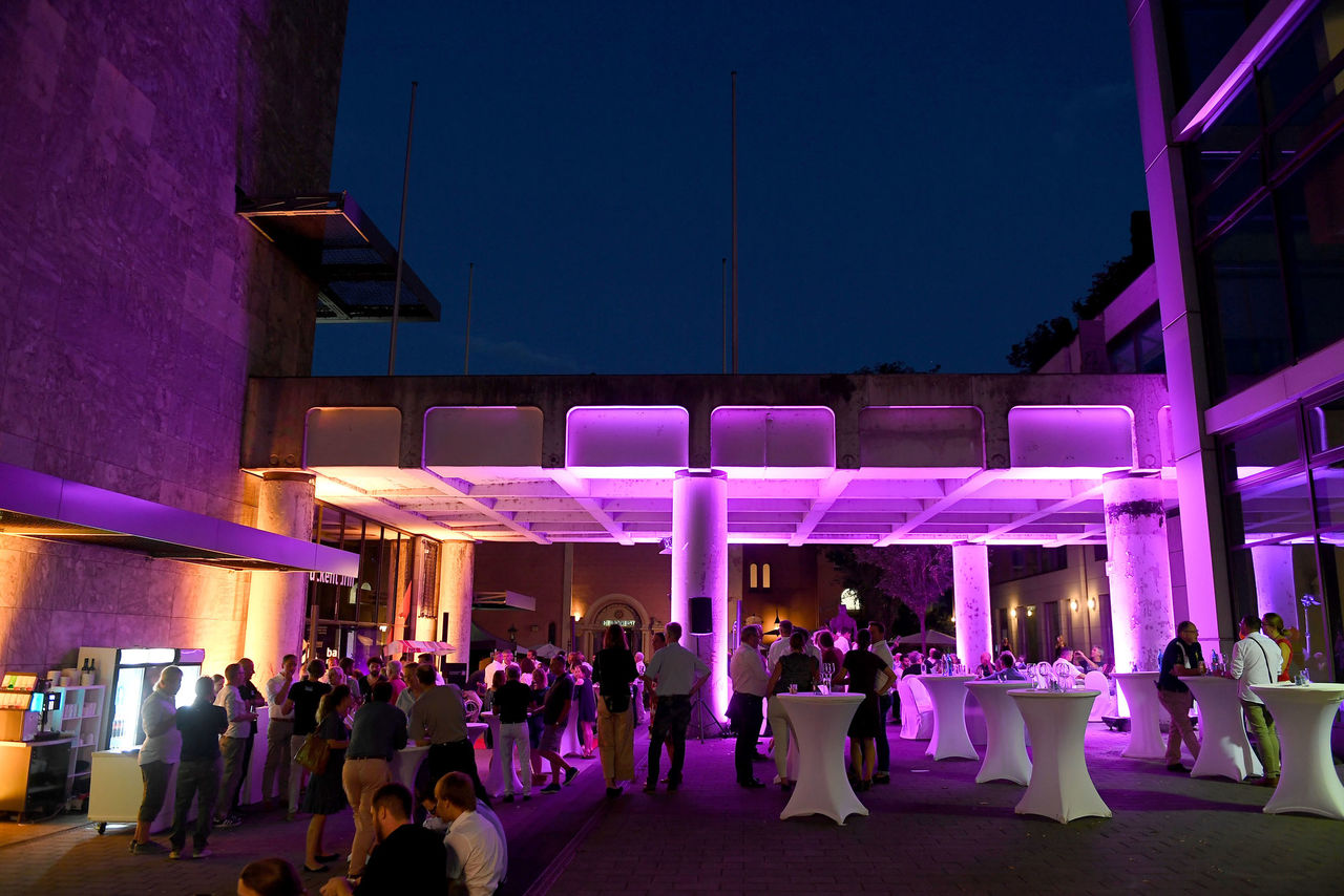 Der Veranstatungsort (Brückenturm) bei Dunkelheit, in stimmungsvollen Farben (violett/blau/orange) beleuchtet.