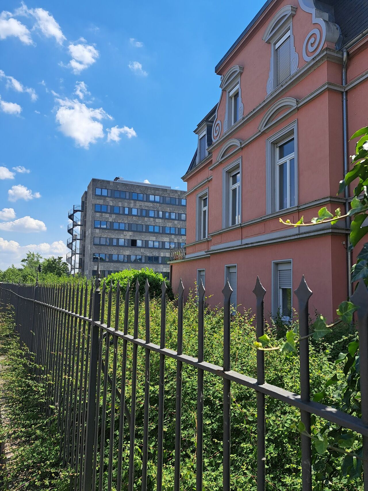 im Vordergrund ein historischer Altbau, im Hintergrund ein Hochhaus mit schlichter funktionaler Fassade.