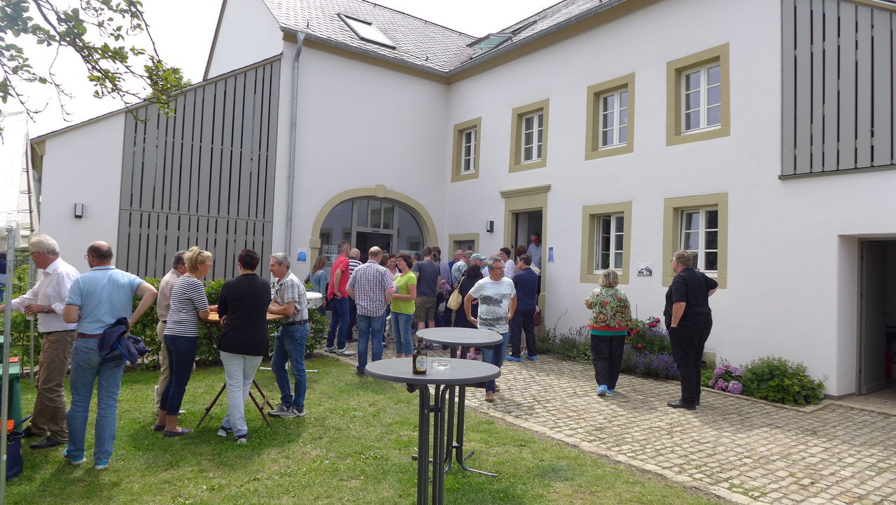 Besuchergruppe beim Tag der Architektur auf der Wiese vor dem ehem. Bauernhof
