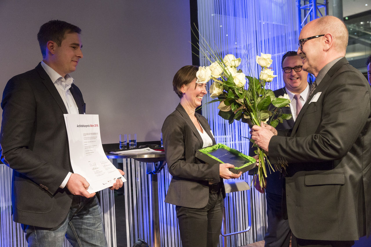 Innenarchitektin Carolin Seegmüller, Werkgemeinschaft Landau und Bauherr Andreas Meyer vom Weingut Meyer, Heuchelheim-Klingen / Pfalz, nehmen Urkunde, Plakette und Blumen von Staatssekretär Andy Becht und Kammerpräsident Gerold Reker in Empfang.