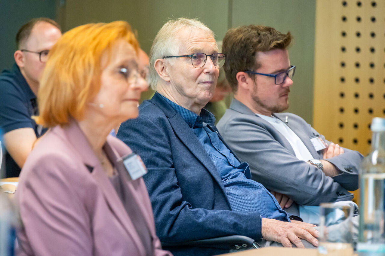 Sabine Hahn, Joachim Exler (Vorstand Architektenkammer Hessen) und Stefan Lawall sitzen in der ersten Reihe des Publikums.