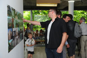 Besucher des Vortrags "Kunst der Bausünde" sehen sich die collagenartigen, großformatigen Plakate an.