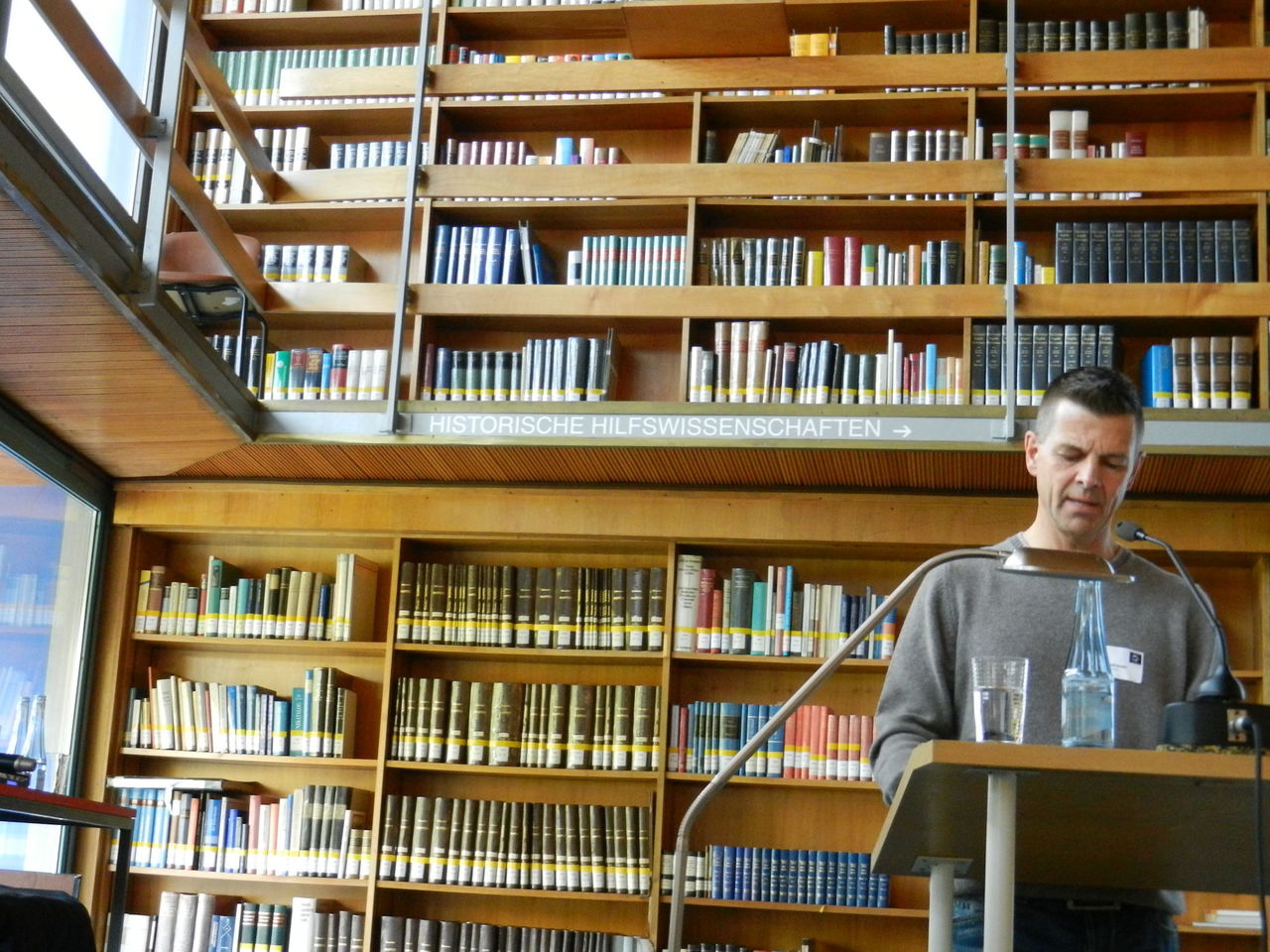 Foto vom zweiten Sprecher der Veranstaltung vor einer großen Bücherwand stehend.