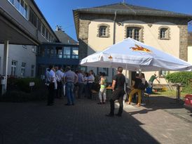 Innenhof des Rathauses (historische Gebäude) mit Biergarnituren und großem Sonnenschirm.