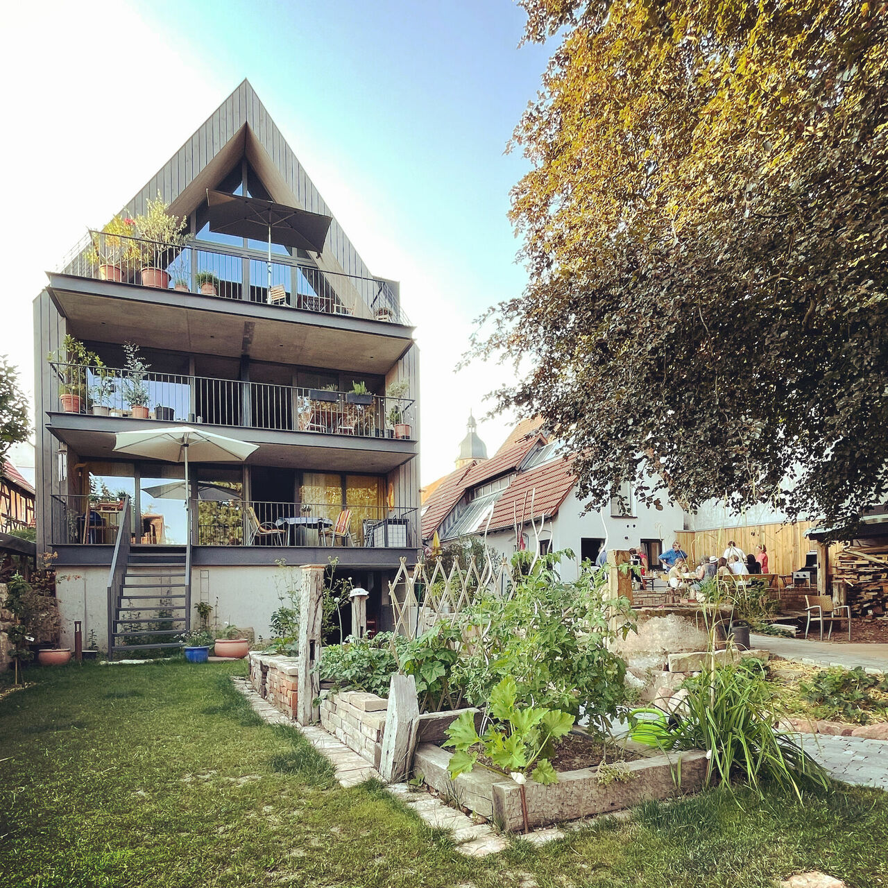 Blick über den Garten auf die Giebelwand mit Balkonen