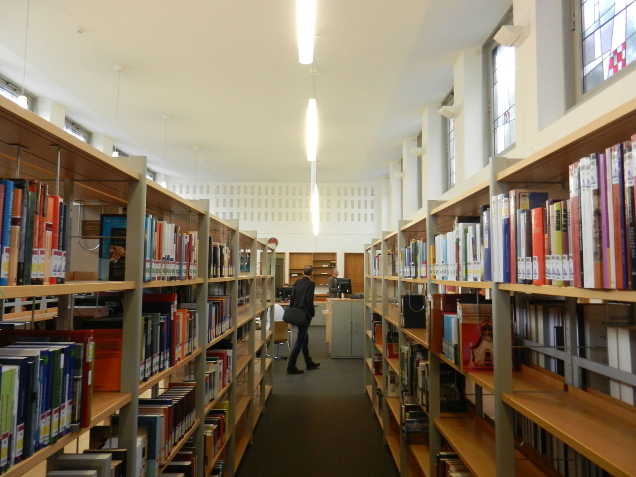 Foto des Bibliotheksbereich des Veranstaltungsortes, mit Blick auf einen Gang, links und rechtes an den Seiten befinden sich Bücherregale.