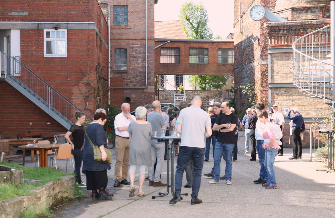 Blick auf die Gebäude der "Alten Papuerfabrik" mit Backsteinfassaden, davor eine Besichtigungsgruppe.