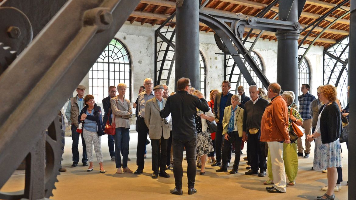 Besuchergruppe in der Ebene der Dachkonstruktion aus Stahlfachwerkträgern und Stahlsäulen