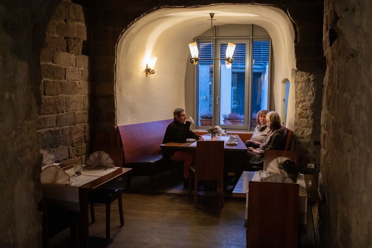 Blick auf einen Tisch mit drei Personen in einer gemütlichen Mauernische.