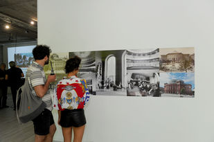 Foto: Kristina Schäfer, Mainz Die Collage zeigtBlick auf die Wand mit Fotos des heutigen Mainzer Staatstheaters aus verschiedenen Zeiten. Im Vordergrund zwei Besucher von hinten die Collage betrachtend.